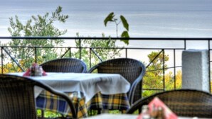 Eine Terrasse mit Korbstühlen und einem Tisch, mit Blick auf ein Gewässer.