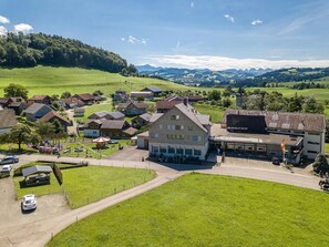 A rural village with houses, a central building with a balcony, and a clear view of the surrounding hills.