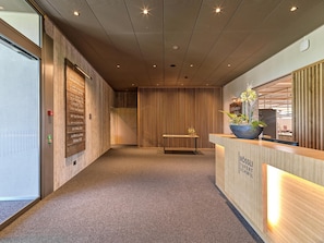A reception area with a wooden reception desk, a bench, and a wall with vertical wooden slats.