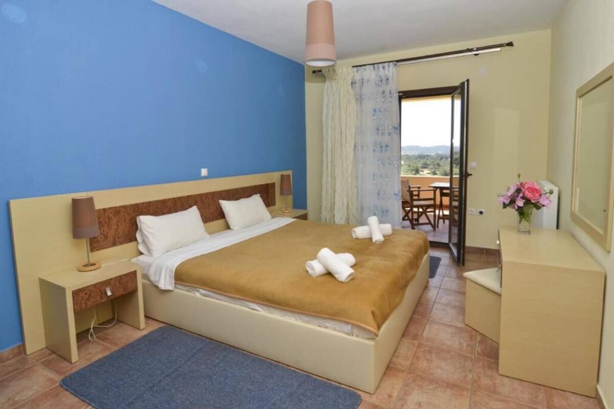 A hotel room with a bed, bedside table, and a desk with a chair.