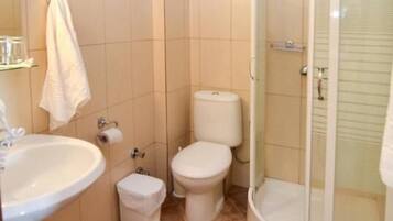 A compact bathroom with a sink, toilet, and shower.