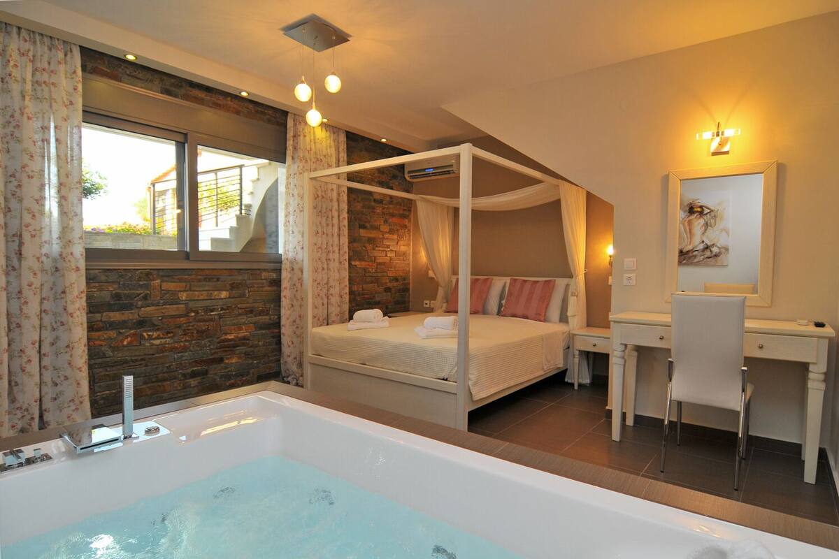Une chambre à coucher avec un lit à baldaquin, un bureau et une grande baignoire.