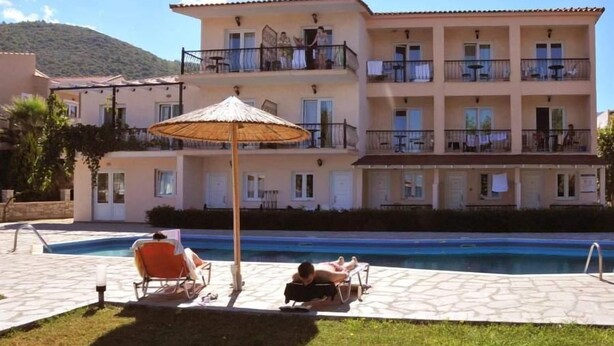 A multi-story hotel with a swimming pool, outdoor seating, and a mountain backdrop. - Sunrise Beach (Thasos)