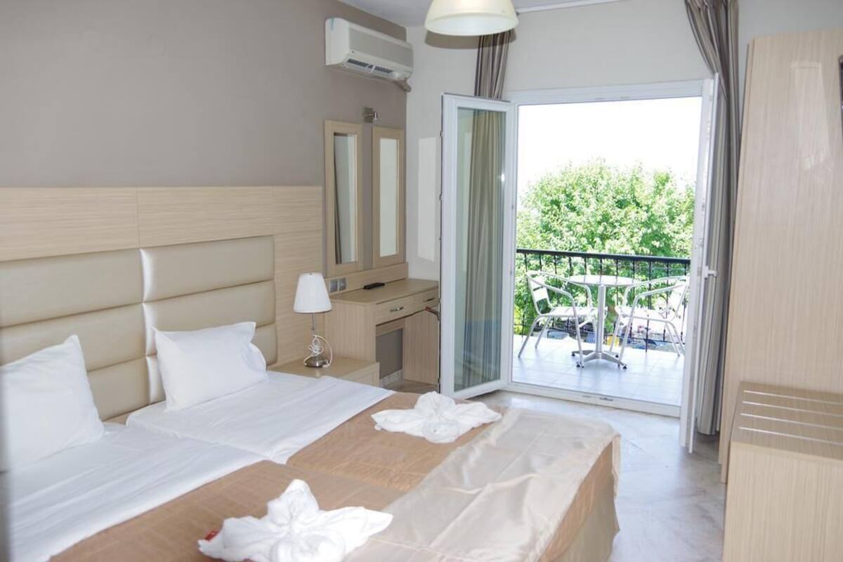 Ein Hotelzimmer mit einem großen Bett, einem Schreibtisch, einem Stuhl und einem Balkon mit Gartenmöbeln.