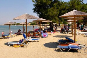 A beach with sun loungers and umbrellas, a clear sky, and a calm sea. - Sunrise Beach (Thasos)
