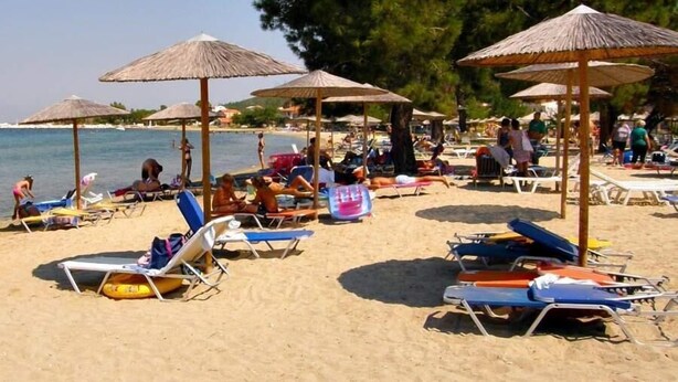 A beach with sun loungers and umbrellas, a clear sky, and a calm sea. - Sunrise Beach (Thasos)