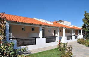A row of white buildings with orange-tiled roofs and black railings. - Sunrise Beach (Thasos)