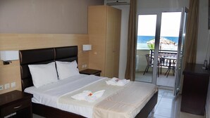 A hotel room with a large bed, a wardrobe, a nightstand, and a balcony with a view of the sea. - Sunrise Beach (Thasos)