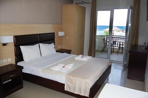 A hotel room with a large bed, a wardrobe, a nightstand, and a balcony with a view of the sea. - Sunrise Beach (Thasos)