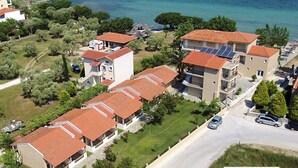 A coastal residential area with multiple two-story buildings, some with balconies, and a road with cars. - Sunrise Beach (Thasos)