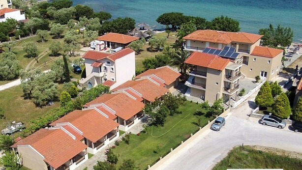 A coastal residential area with multiple two-story buildings, some with balconies, and a road with cars. - Sunrise Beach (Thasos)