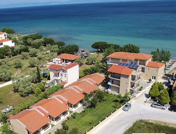 A coastal residential area with multiple two-story buildings, some with balconies, and a road with cars. - Sunrise Beach (Thasos)