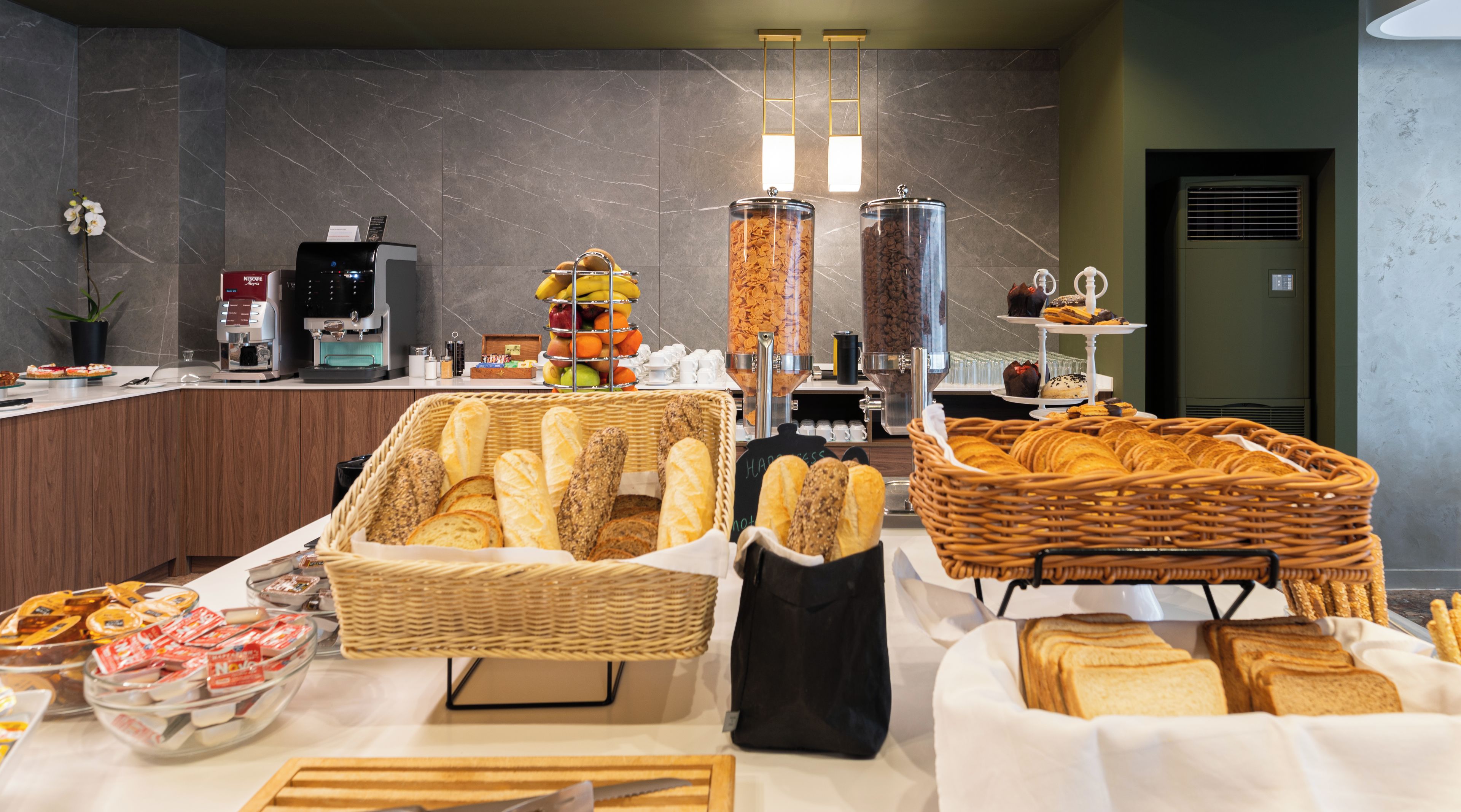 A breakfast buffet with various breads, pastries, and a coffee station.