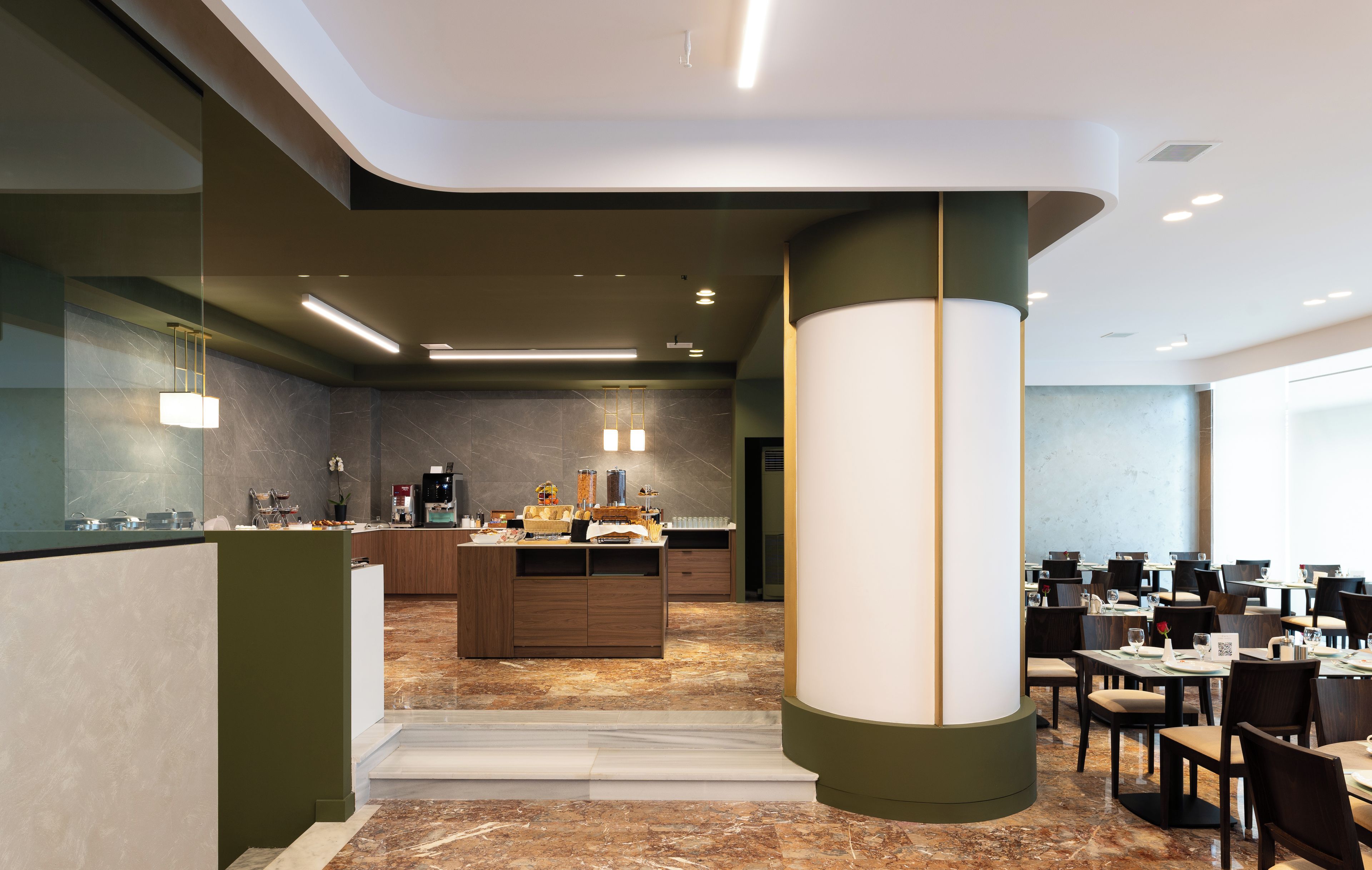 A modern hotel lobby with a central bar area, seating arrangements, and a marble floor.