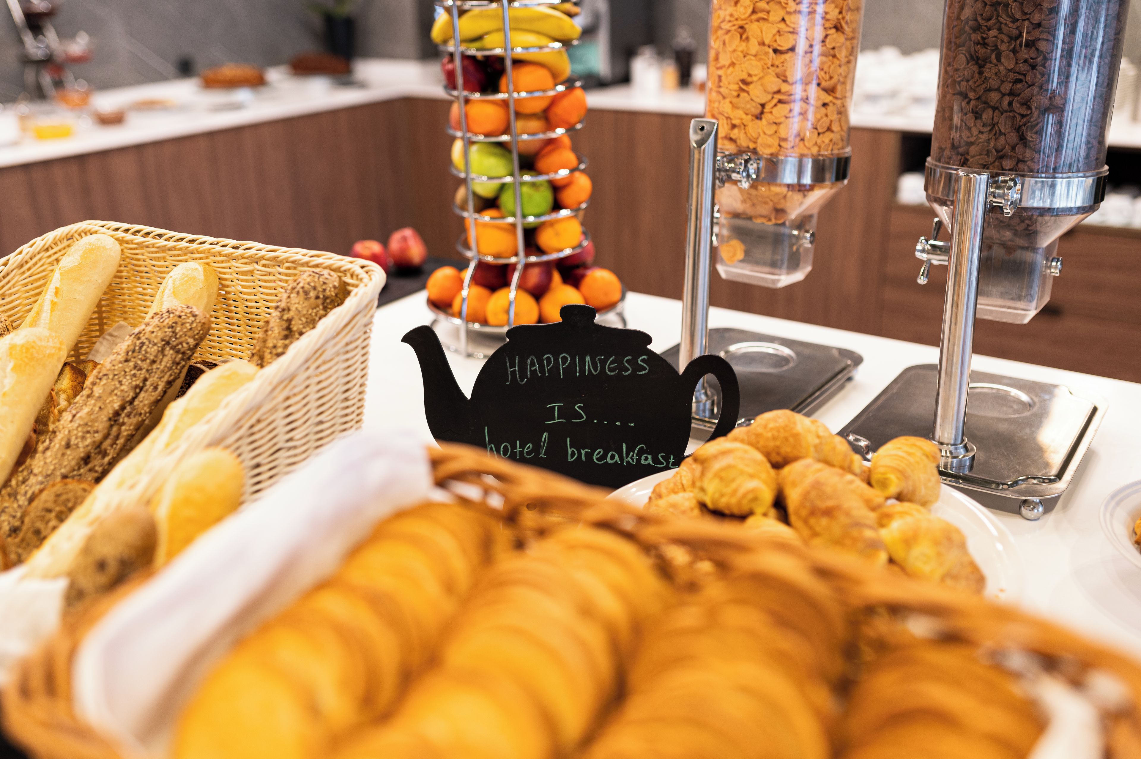 A breakfast buffet with bread, pastries, and fruit.