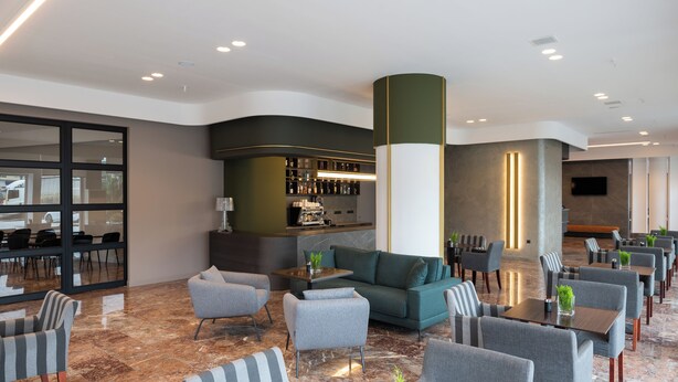 A modern lobby with a bar area, seating arrangements, and a large screen.