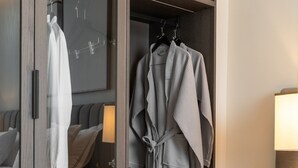 Une armoire avec un miroir, une robe suspendue et une petite table avec une lampe.