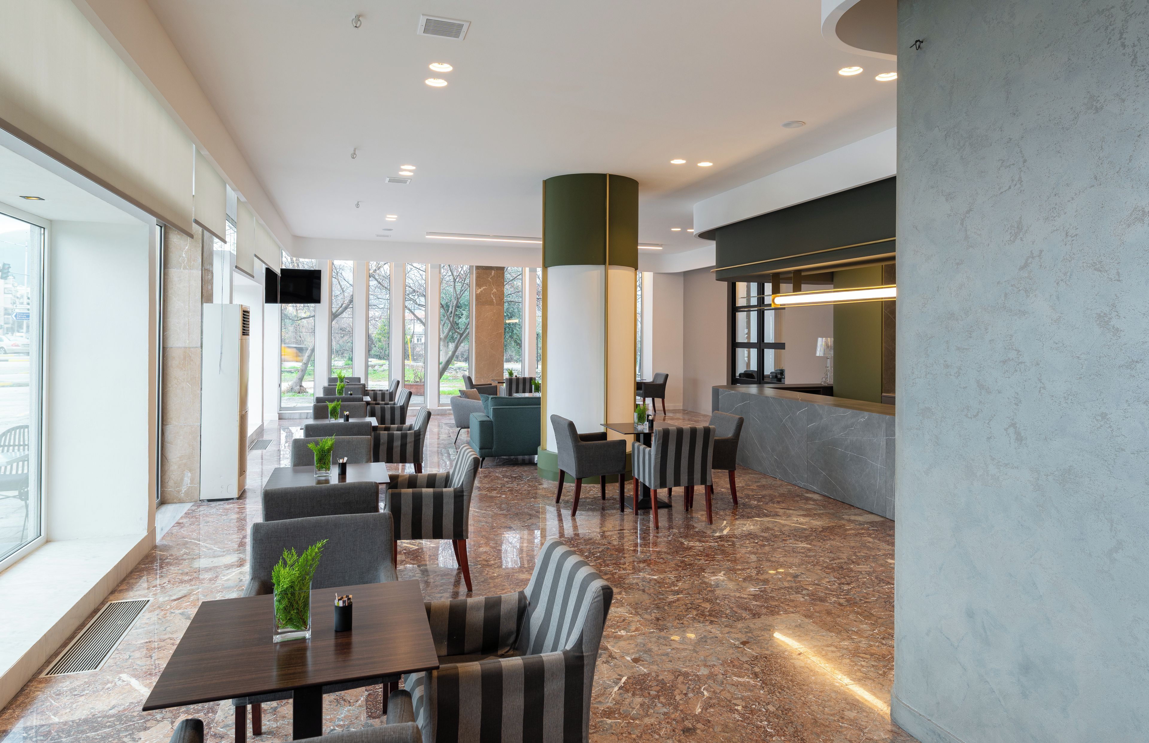 A modern hotel lobby with seating, a reception desk, and large windows.