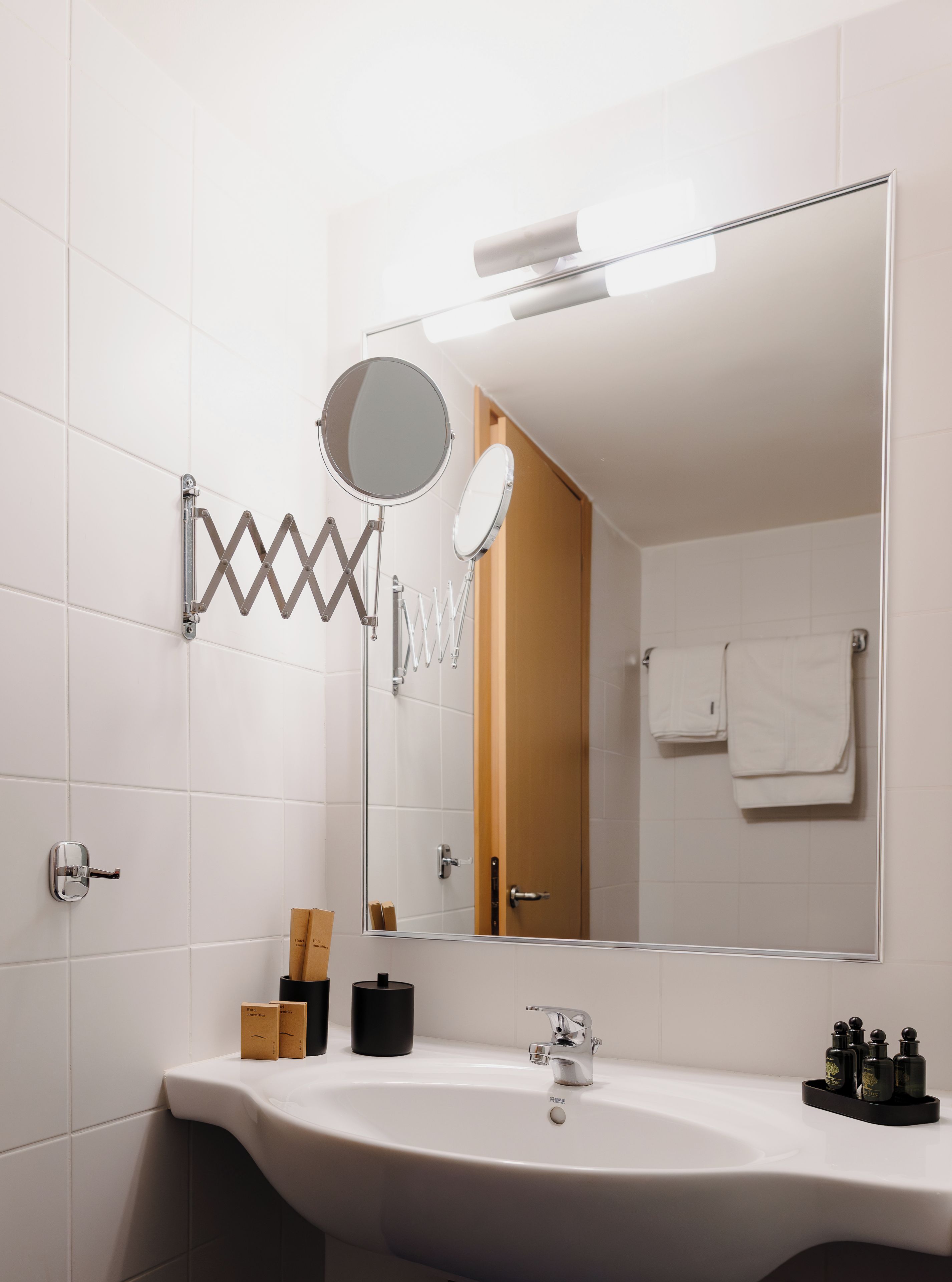 A bathroom with a white sink, a mirror, a towel rack, and a door.