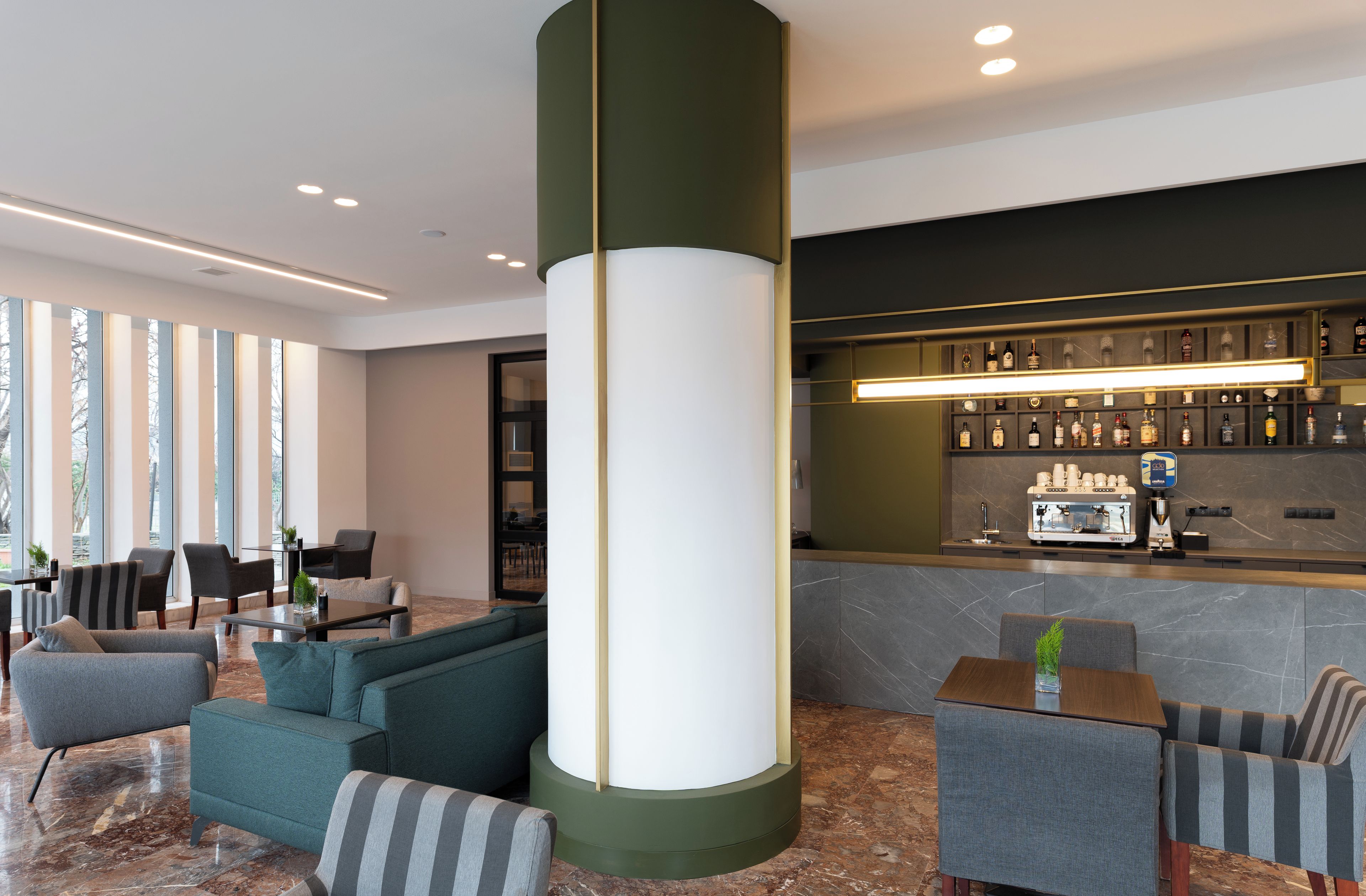 A modern lobby with seating, a bar area, and a large pillar.