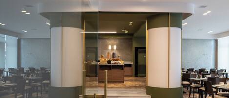 A modern hotel lobby with a central reception desk, marble flooring, and glass partitions.