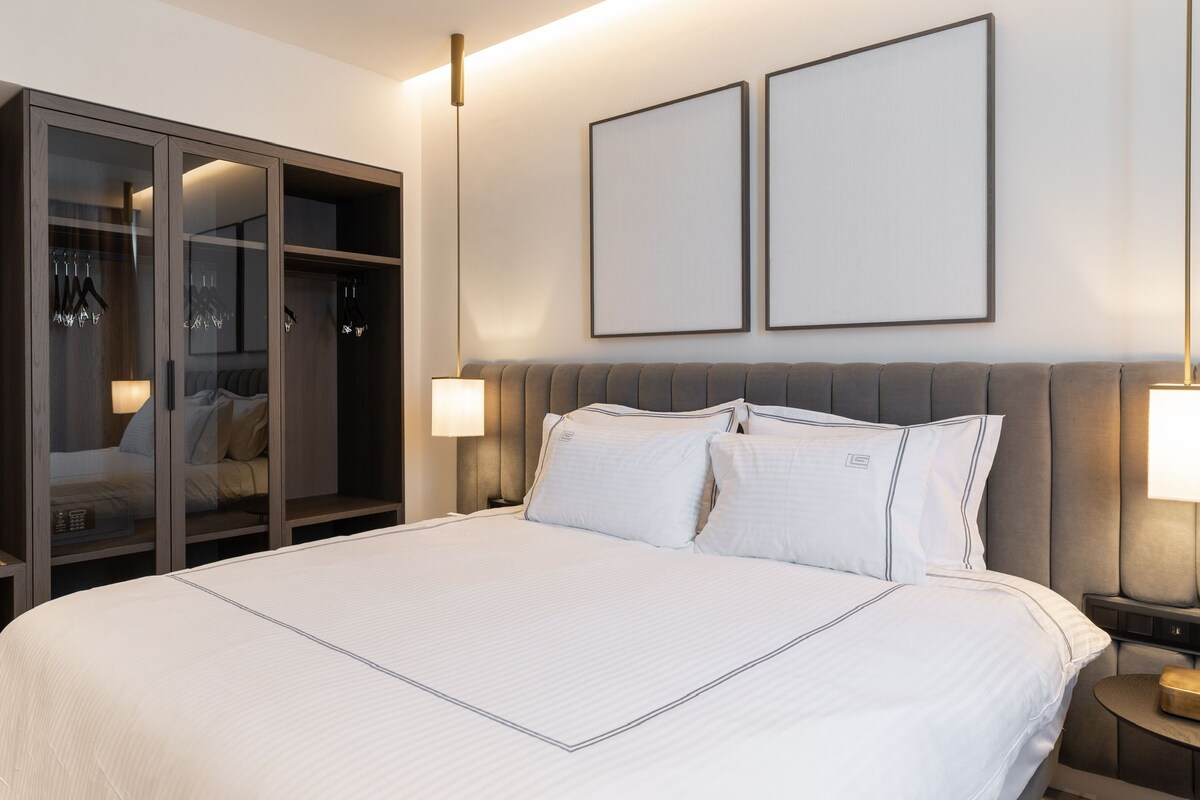 Una habitación de hotel con una cama grande, un armario y dos cuadros en la pared.