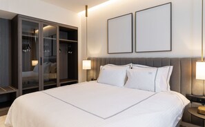 Ett hotellrum med en stor säng, en garderob och två inramade tavlor på väggen.