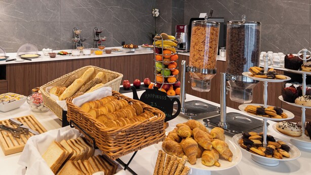 Un buffet proposant une variété de plats, notamment du pain, des pâtisseries et des fruits.
