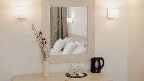 Une salle de bain avec un miroir, un vase contenant des branches, une machine à café et deux verres posés sur un plateau.