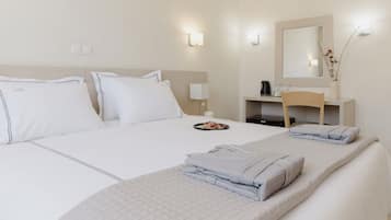 Une chambre d’hôtel avec un lit, une table de chevet, un miroir et une petite table sur laquelle se trouve un vase.