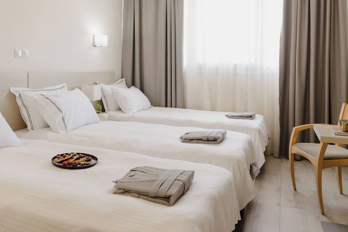 A hotel room with two beds, a small table, and a chair.