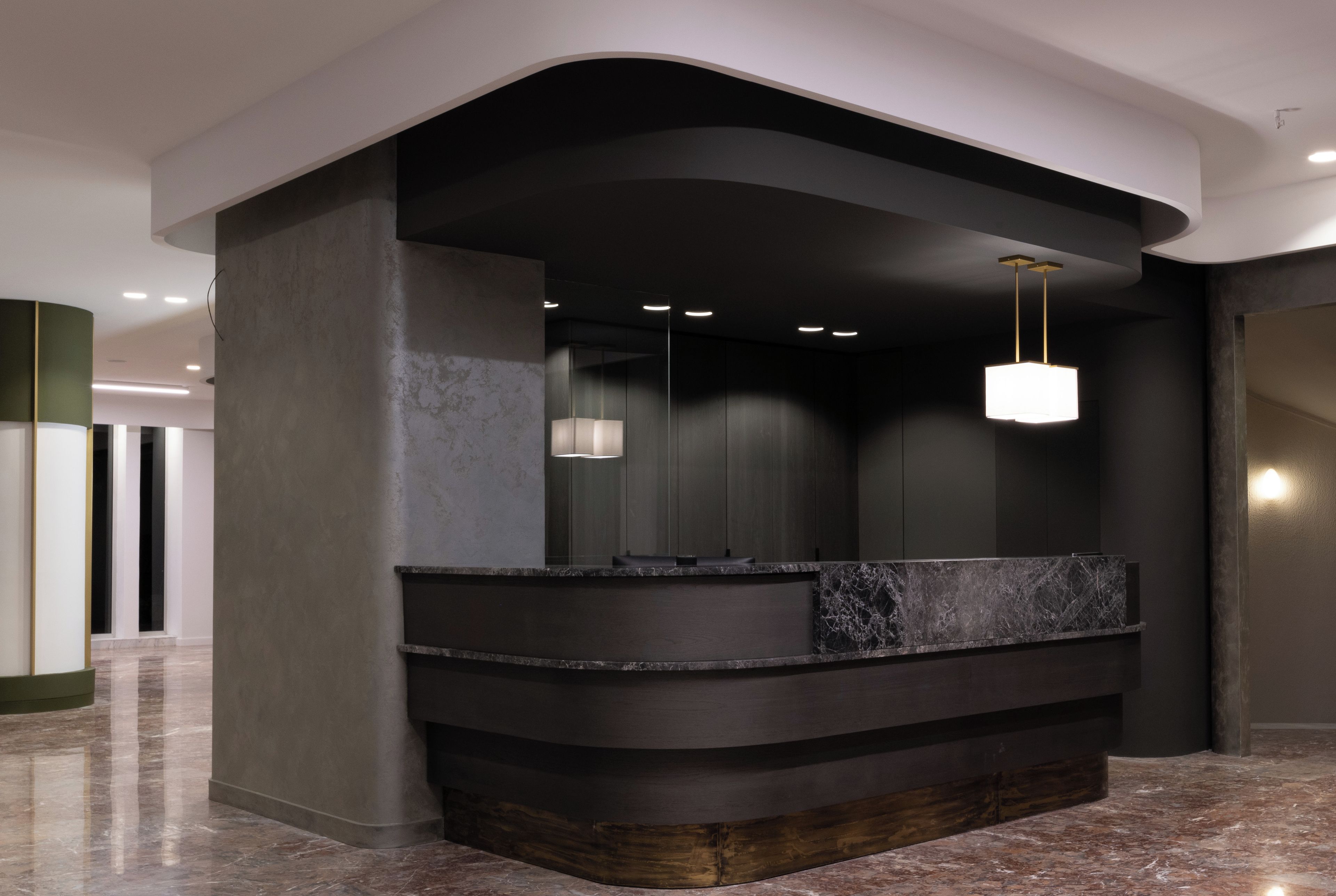 A modern reception area with a curved reception desk, marble countertop, and pendant lighting.