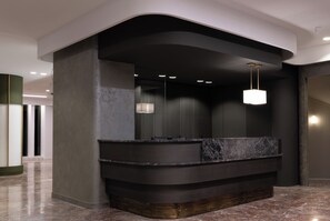 A modern reception area with a curved reception desk, marble countertop, and pendant lighting. - Nestos (Xanthi)