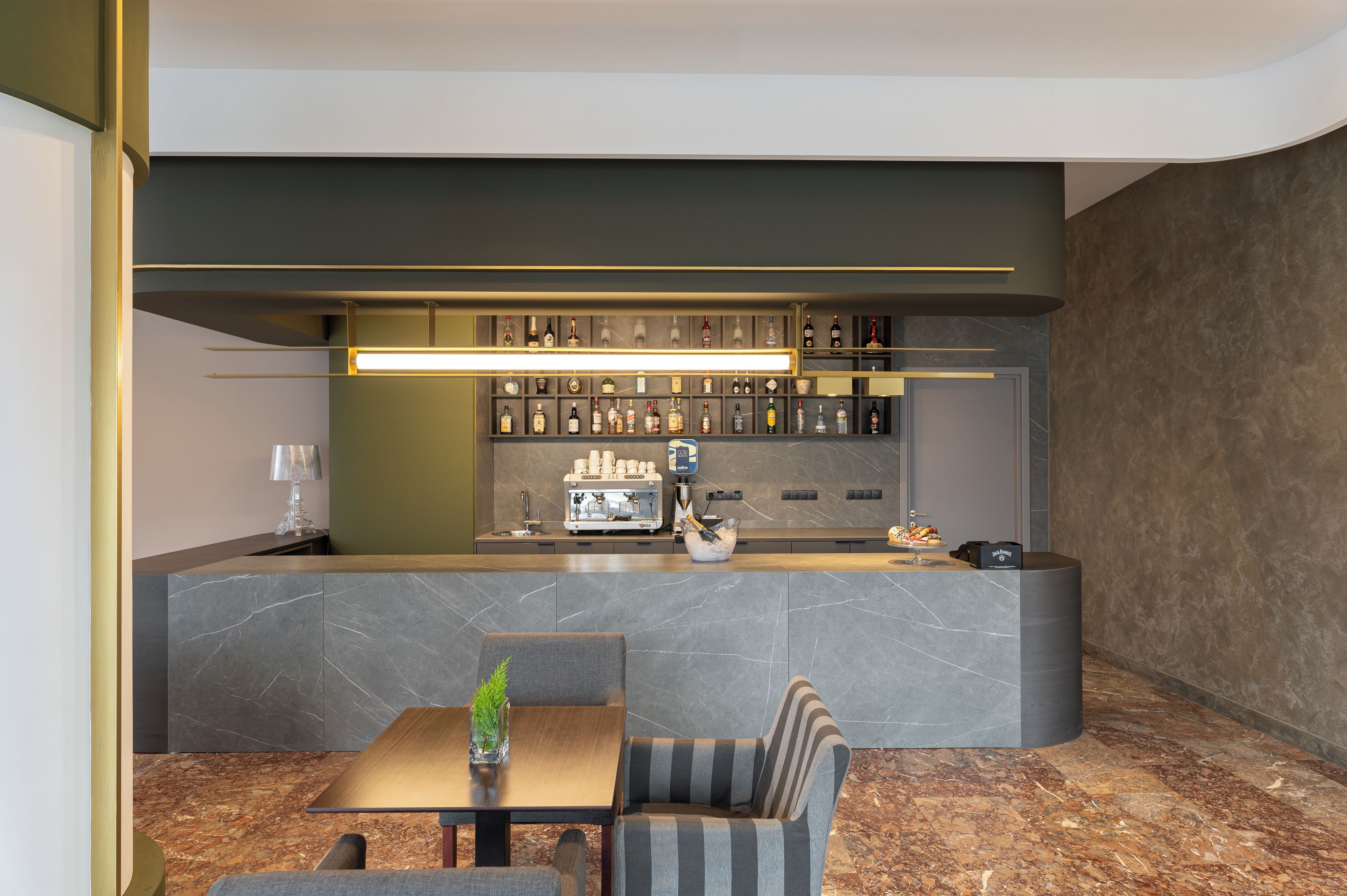 Eine moderne Bar mit einer Marmorplatte, Sitzgelegenheiten und einer gut sortierten Spirituosenregal.