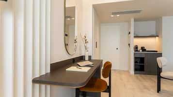 A modern room with a dining table, chairs, a mirror, and a kitchen area.