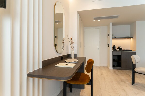 Quarto moderno com mesa de jantar, cadeiras, espelho e cozinha.