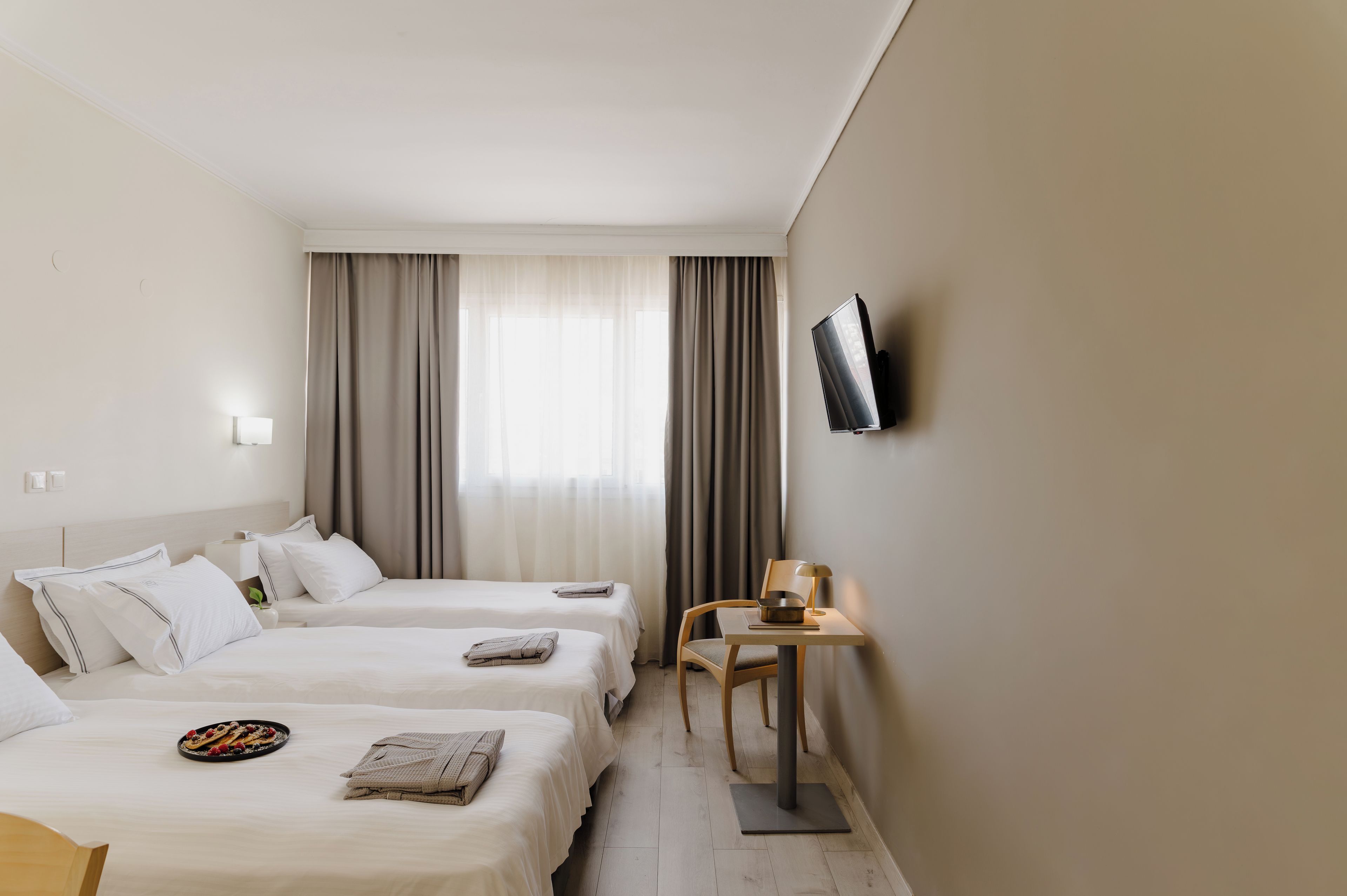 A hotel room with two beds, a TV, a desk, and a chair.