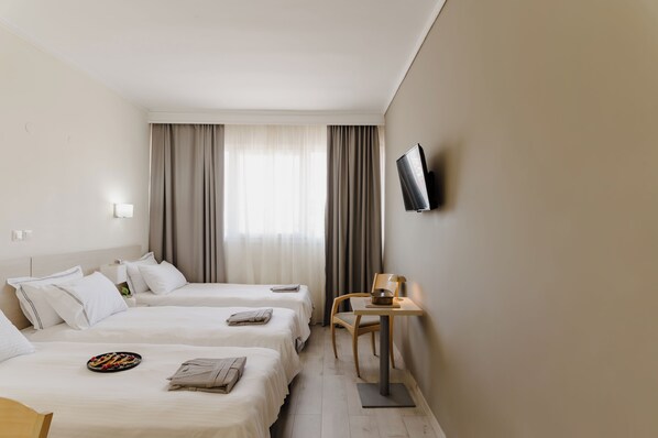 Habitación de hotel con dos camas, televisión, escritorio y una silla.