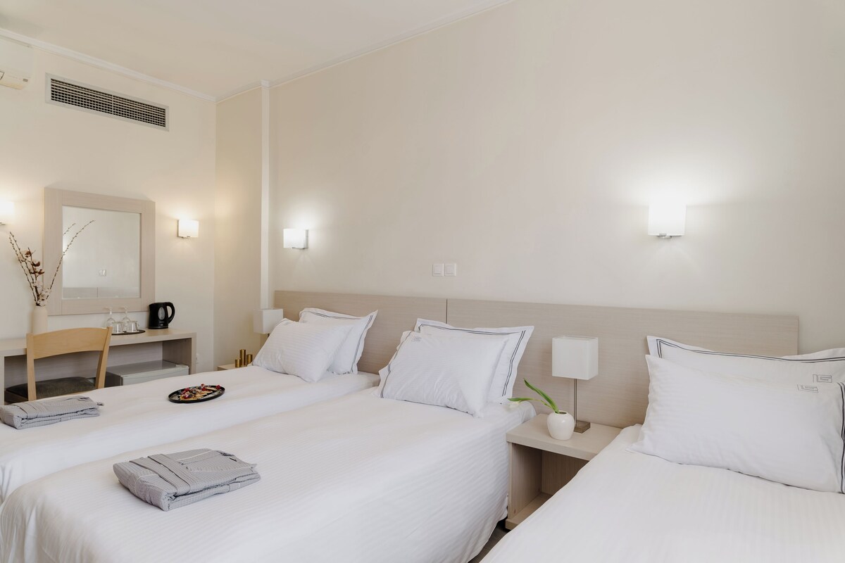 Habitación de hotel con dos camas, un escritorio, una silla, un espejo y luces en la pared.