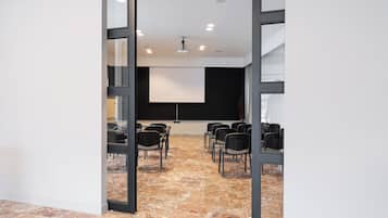 A conference room with a projector screen, black chairs, and a marble floor.