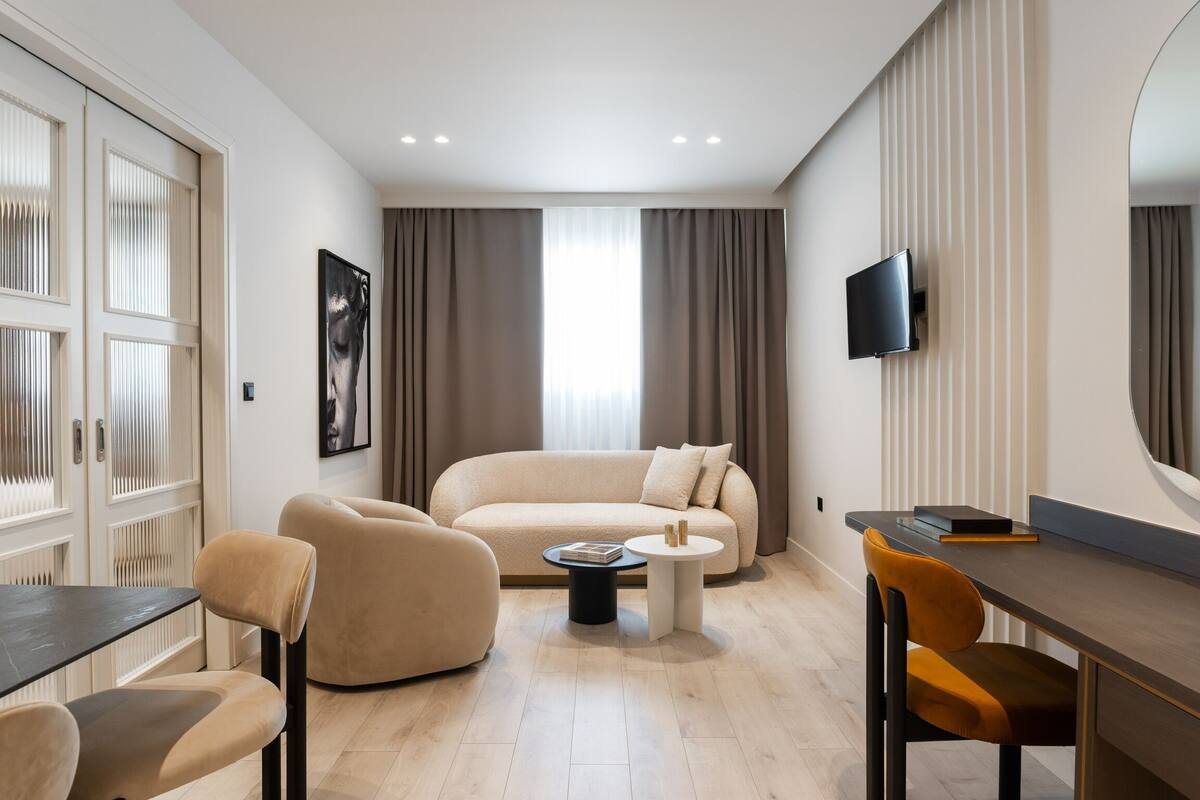 A modern living room with a sofa, chairs, a coffee table, a TV, and a desk.