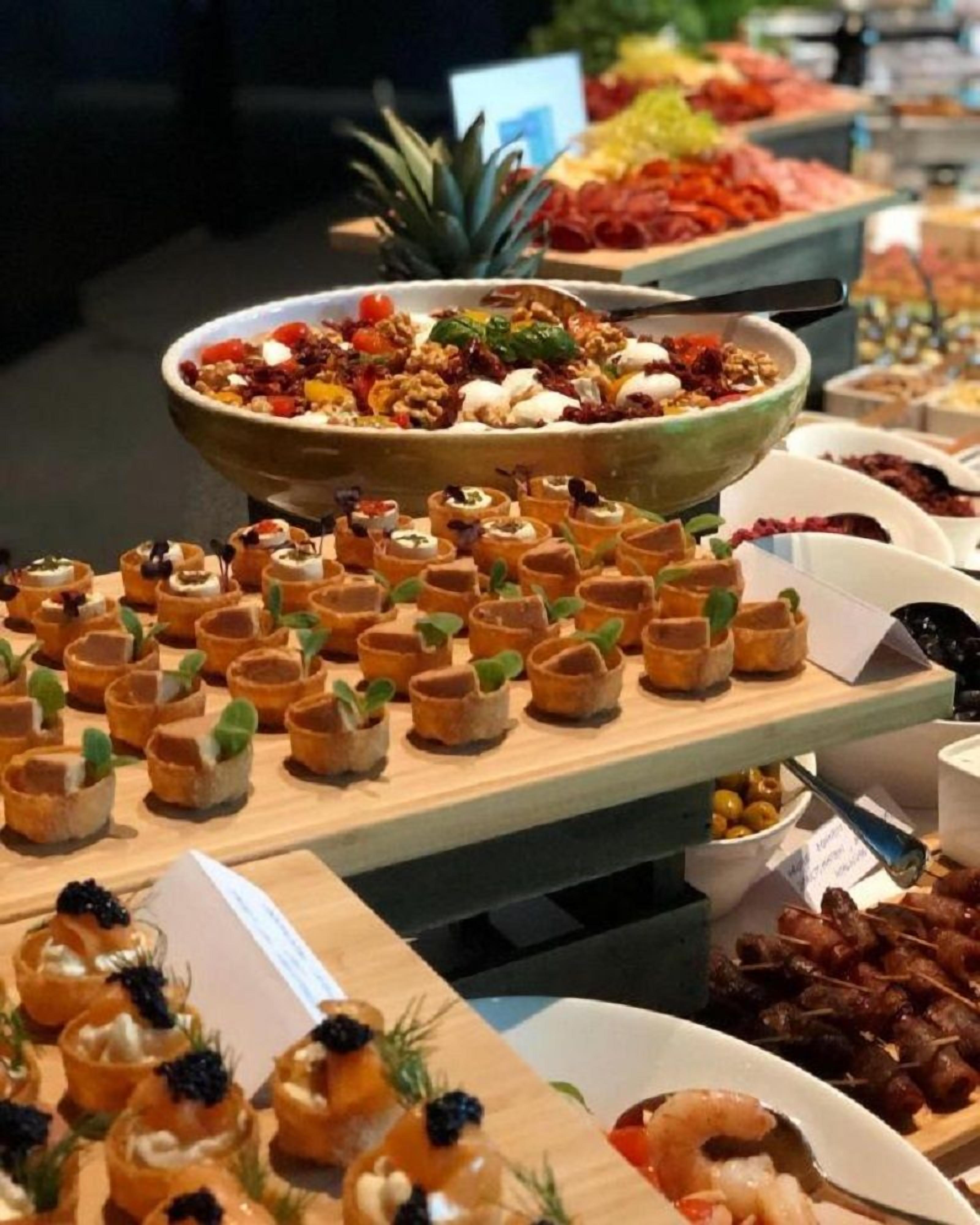 A buffet with various food items including a large bowl of mixed fruits and nuts, small appetizers, and skewered meats.