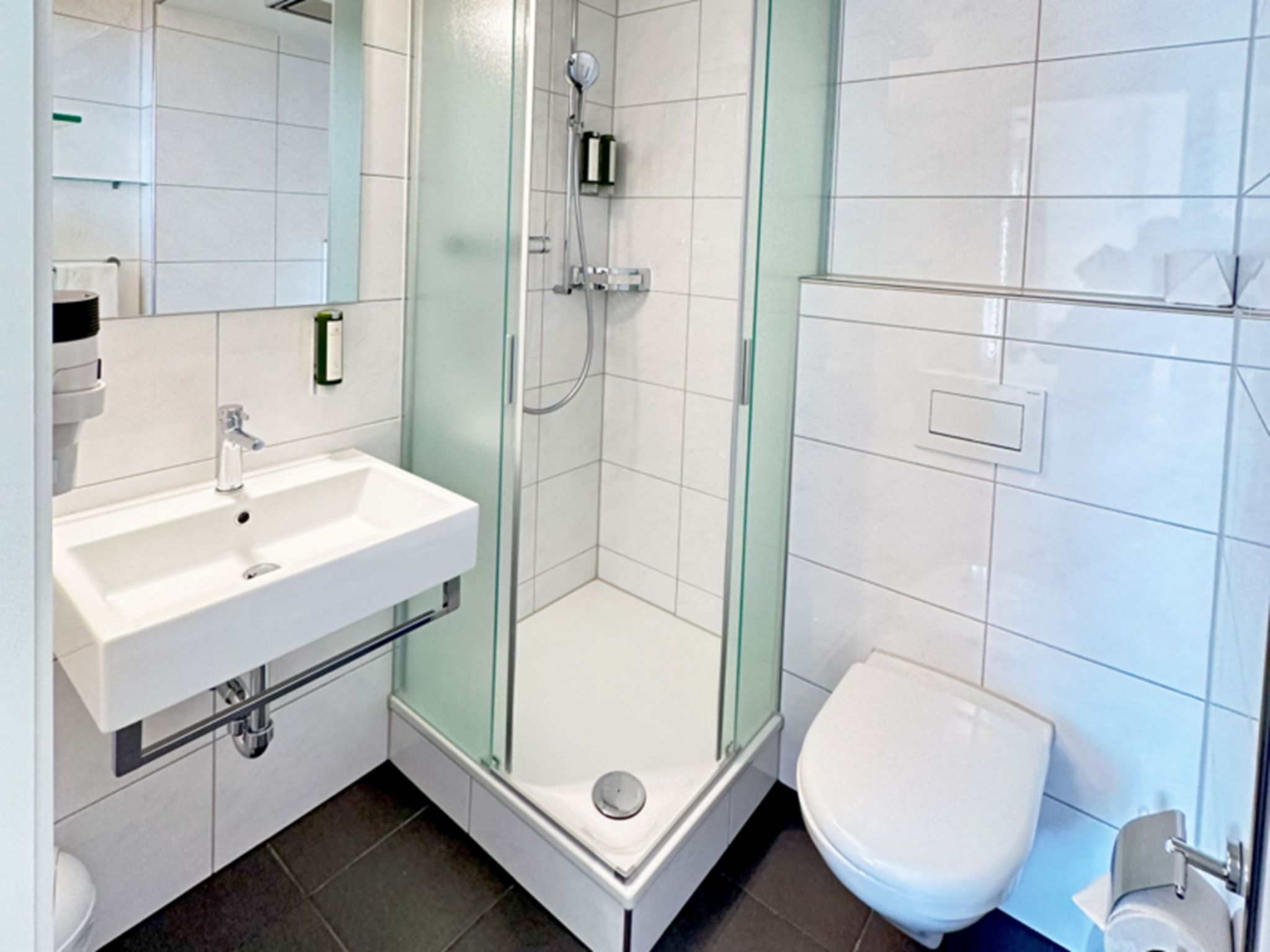 Ein modernes Badezimmer mit einer einteiligen Duschkabine, einem weißen Waschbecken und einer Toilette.