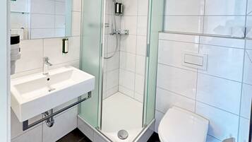 Ein modernes Badezimmer mit einer einteiligen Duschkabine, einem weißen Waschbecken und einer Toilette.