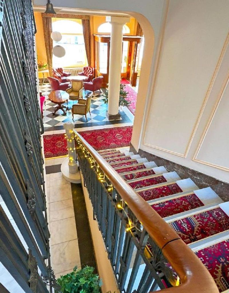 Un magnifique escalier avec des rampes richement décorées et des tapis à motifs.