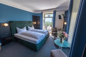 A hotel room with a large bed, a small table with a vase of flowers, a chair, and a balcony with outdoor seating. - Hotel Royal Lucerne (Lucerne)
