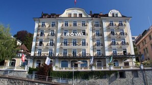 A multi-story hotel with balconies and a flag on top. - Hotel Royal Lucerne (Lucerne)
