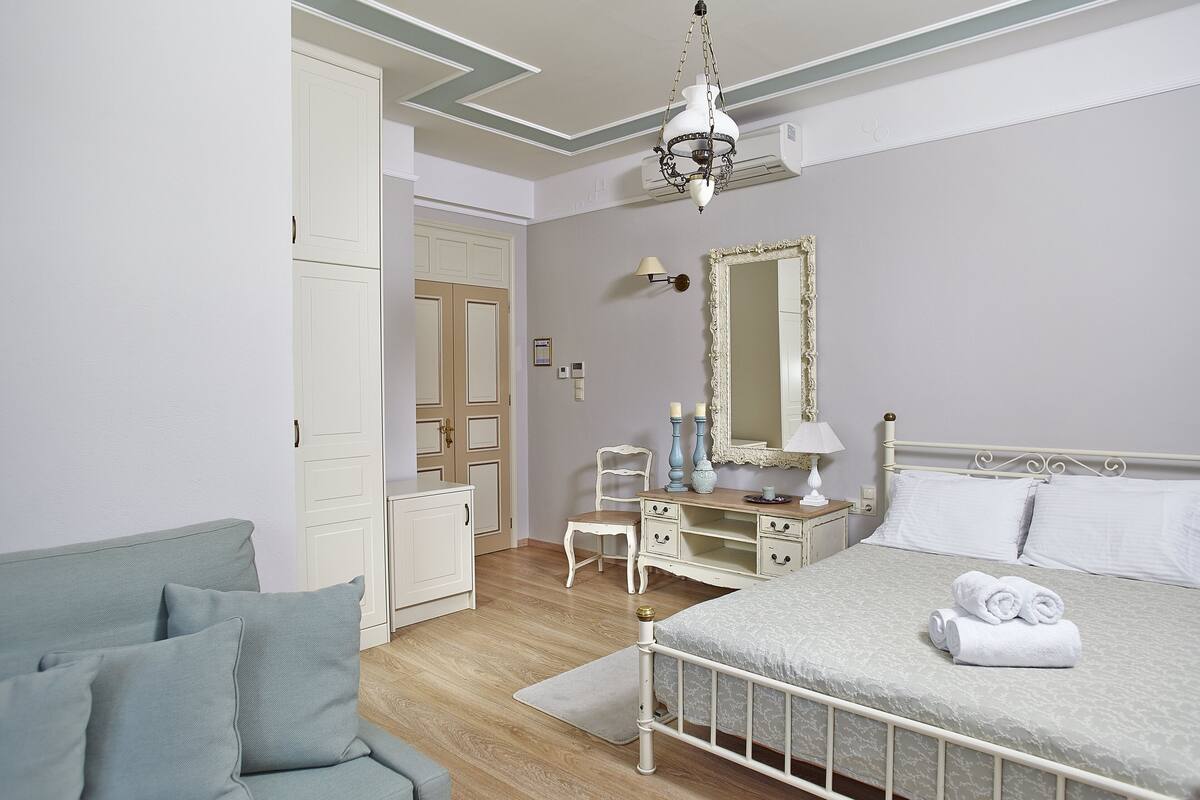 A bedroom with a bed, a dresser, a chair, a desk, and a mirror.