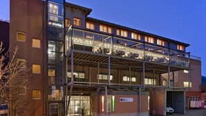 A multi-story building with a glass facade, a covered outdoor area, and a sign that reads "OMPIKA." - Hotel Olympica (Brig)