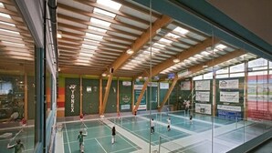 An indoor badminton court with wooden beams and glass walls. - Hotel Olympica (Brig)